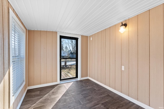 doorway with baseboards, dark wood-style flooring, and wooden walls