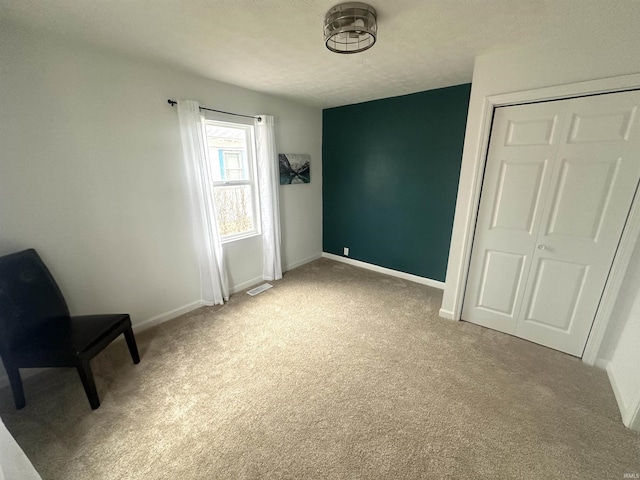 unfurnished bedroom with a closet, light colored carpet, visible vents, and baseboards