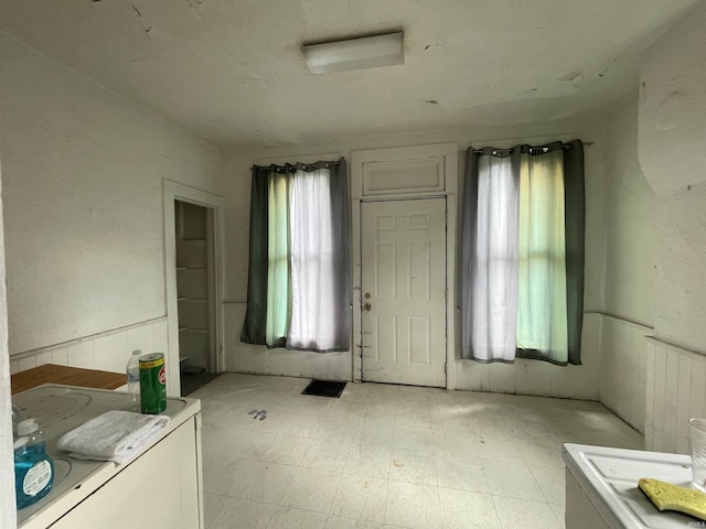 miscellaneous room with a wainscoted wall, light floors, and washer / clothes dryer