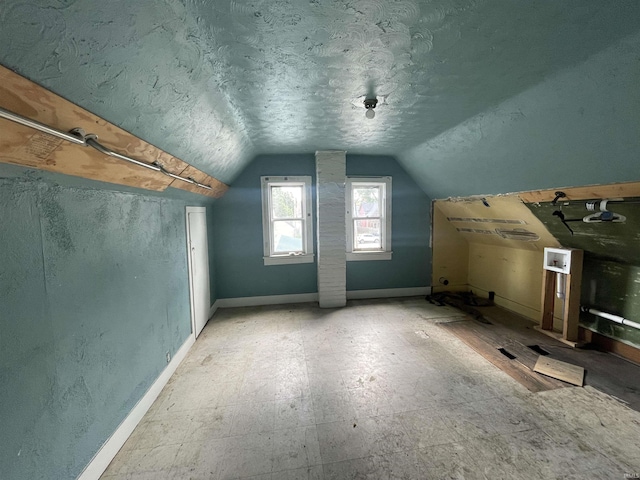 bonus room featuring lofted ceiling, a textured ceiling, and baseboards