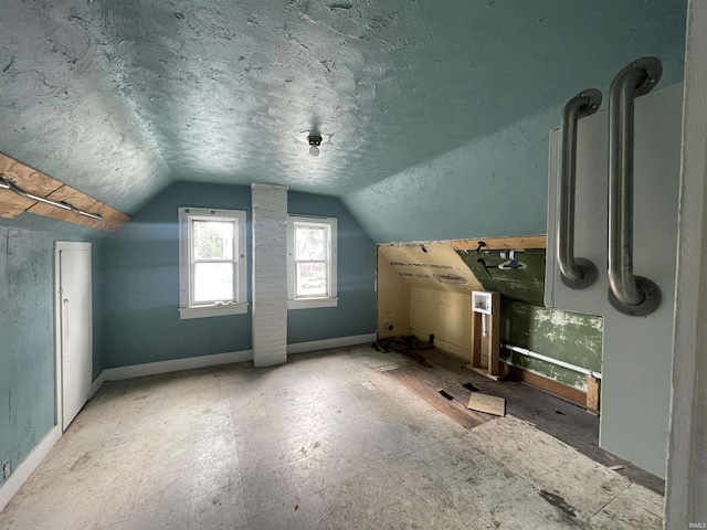 bonus room with lofted ceiling, baseboards, and a textured ceiling