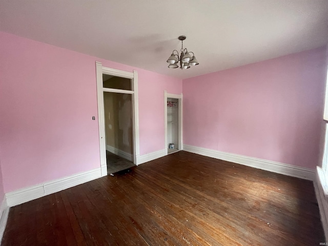 unfurnished bedroom with baseboards, dark wood-type flooring, and a notable chandelier