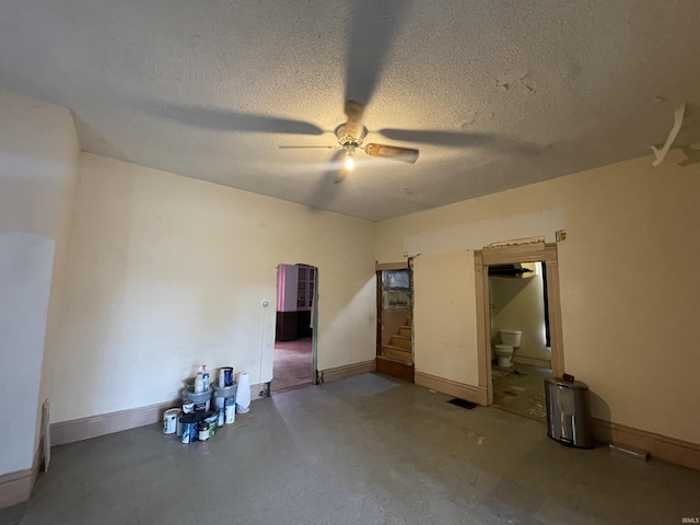 unfurnished bedroom with a ceiling fan, concrete floors, a textured ceiling, and baseboards