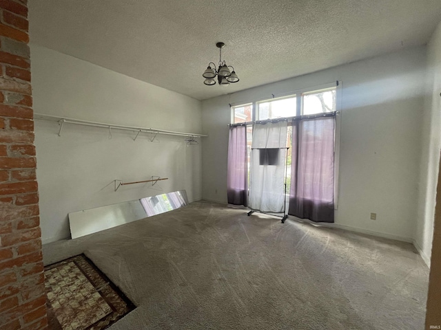 empty room with a textured ceiling, carpet, and an inviting chandelier