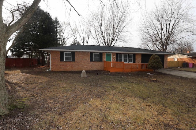 single story home with a wooden deck, fence, and brick siding