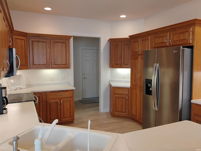 kitchen with recessed lighting, light wood-style floors, light countertops, appliances with stainless steel finishes, and brown cabinetry