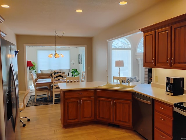 kitchen featuring light countertops, hanging light fixtures, light wood-style flooring, appliances with stainless steel finishes, and a peninsula