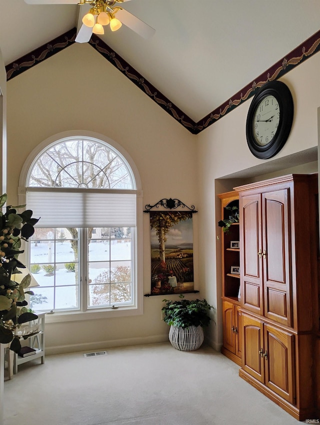 sitting room featuring high vaulted ceiling, visible vents, and light colored carpet