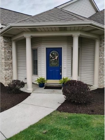 property entrance featuring covered porch and roof with shingles