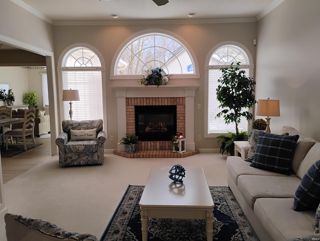 living room with a healthy amount of sunlight, a brick fireplace, crown molding, and carpet flooring