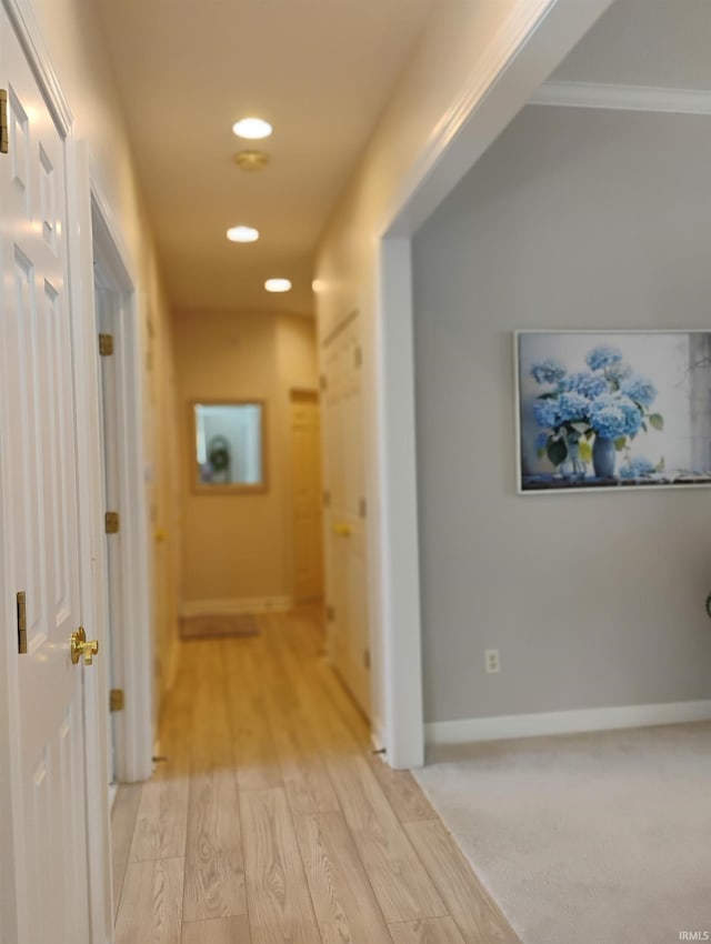 corridor featuring light wood-type flooring, baseboards, and recessed lighting