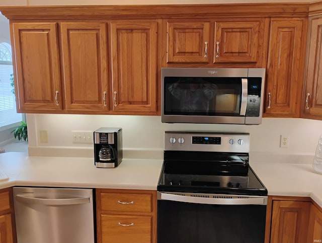 kitchen with stainless steel appliances, brown cabinetry, and light countertops