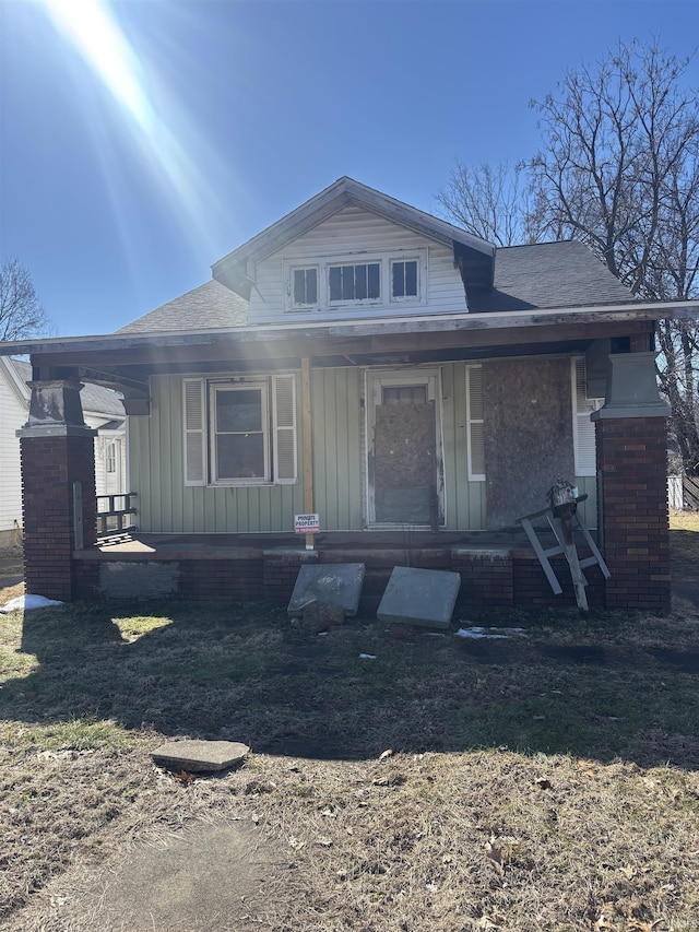 view of front facade with covered porch, roof with shingles, and board and batten siding