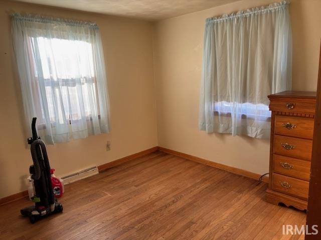 unfurnished bedroom featuring light wood finished floors, baseboards, and baseboard heating