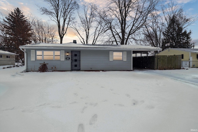 ranch-style home featuring driveway, fence, and an attached carport