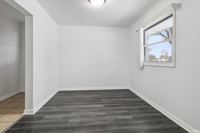 unfurnished room featuring dark wood-type flooring and baseboards