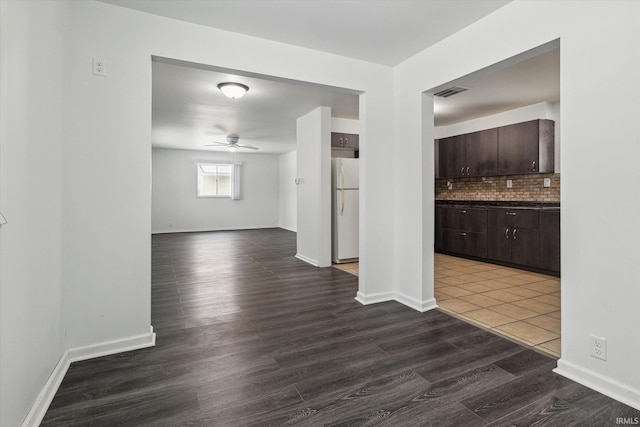 interior space with dark wood-style floors, ceiling fan, visible vents, and baseboards