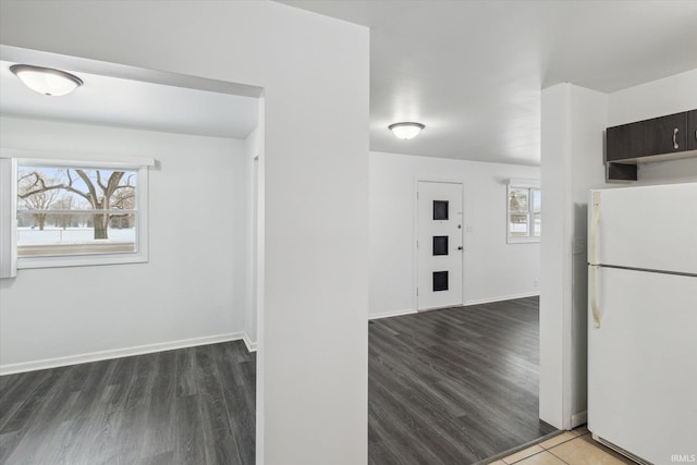 kitchen featuring baseboards, dark wood-style flooring, and freestanding refrigerator