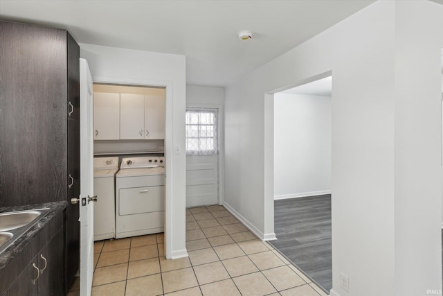 kitchen with light tile patterned floors, baseboards, white cabinets, dark countertops, and washing machine and dryer