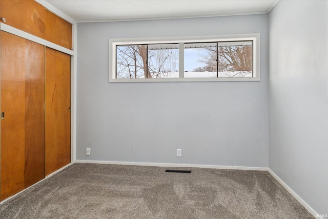 unfurnished bedroom featuring carpet floors, multiple windows, visible vents, and baseboards