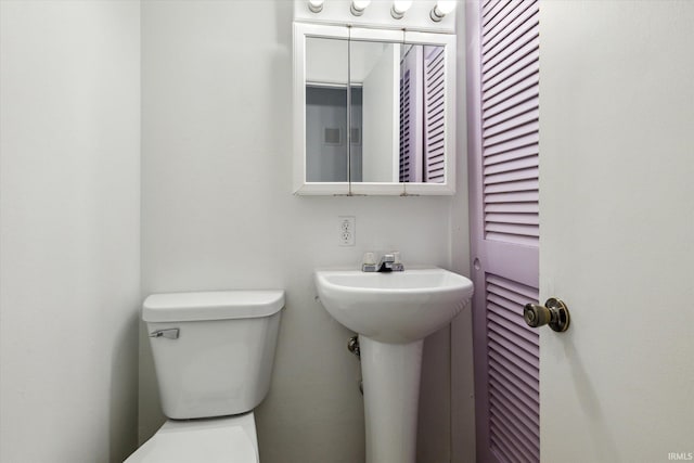 half bathroom featuring a closet, a sink, and toilet