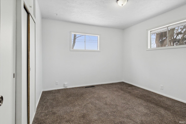 unfurnished bedroom featuring multiple windows, carpet, a closet, and visible vents