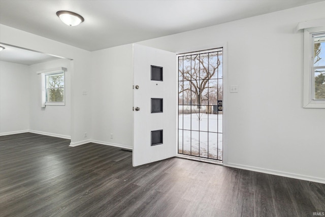 unfurnished room featuring a wealth of natural light, baseboards, and dark wood-style flooring