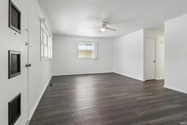 spare room with ceiling fan, baseboards, and dark wood finished floors