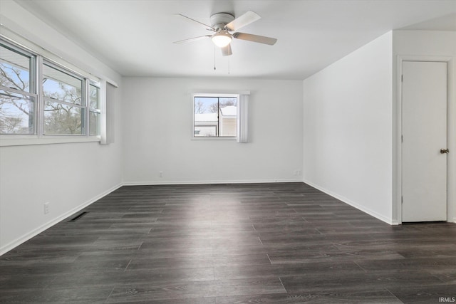 spare room featuring dark wood-style flooring, visible vents, ceiling fan, and baseboards