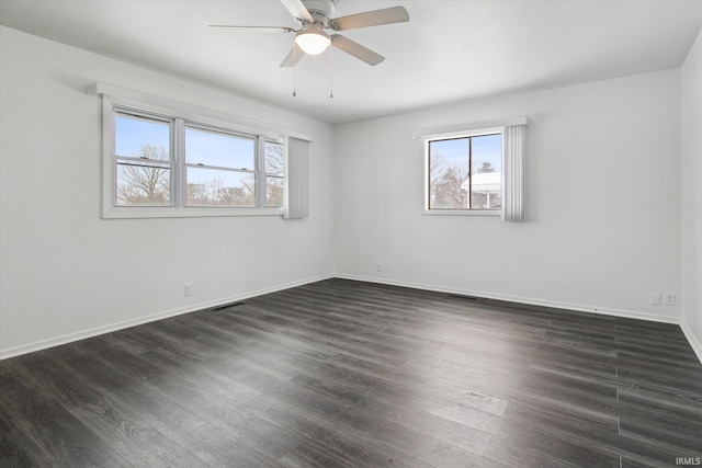 unfurnished room featuring dark wood-type flooring, visible vents, and plenty of natural light