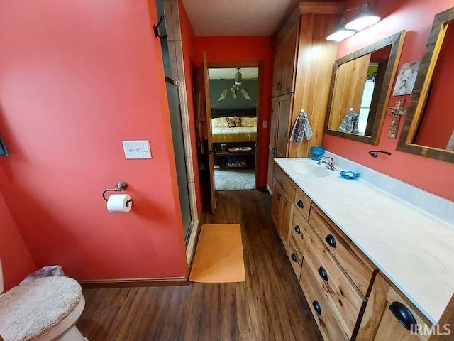 bathroom with toilet, ensuite bathroom, a shower stall, vanity, and wood finished floors