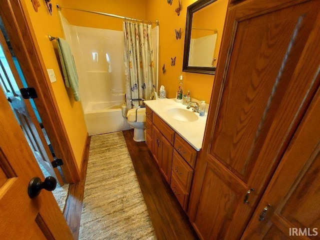 bathroom with toilet, shower / bath combo with shower curtain, wood finished floors, and vanity