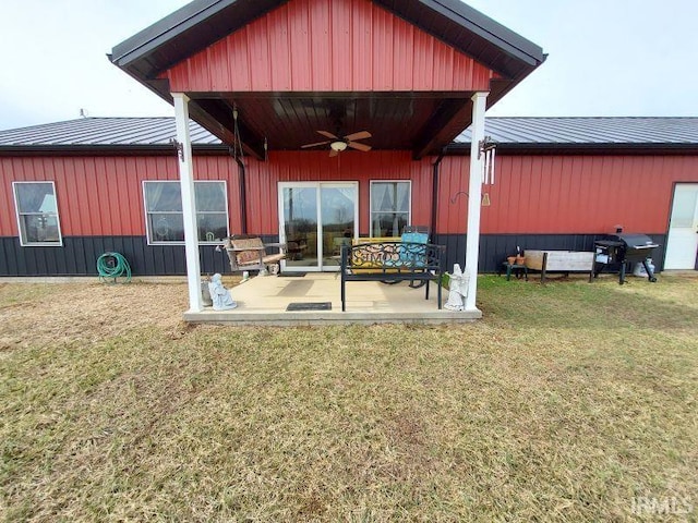 back of property with a ceiling fan, metal roof, board and batten siding, and a lawn