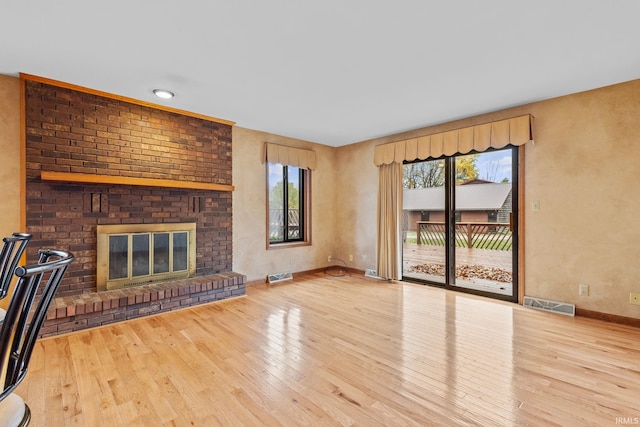 unfurnished living room featuring hardwood / wood-style flooring, baseboards, a fireplace, and visible vents