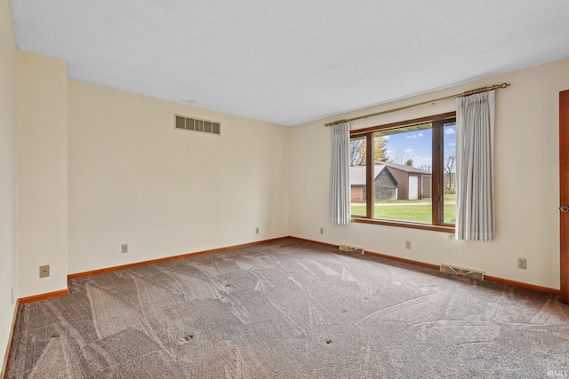 carpeted empty room featuring visible vents and baseboards