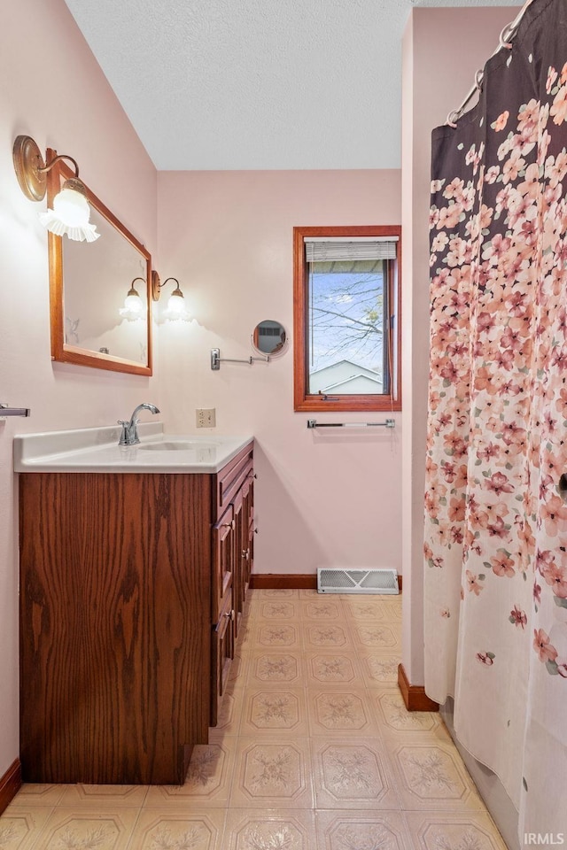 full bathroom with baseboards, visible vents, a textured ceiling, and vanity