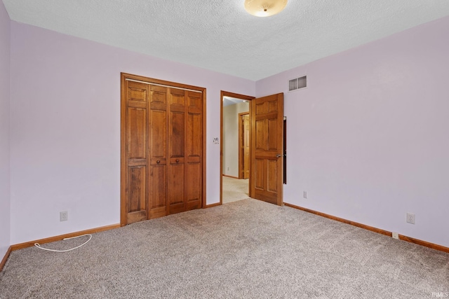 unfurnished bedroom with baseboards, carpet, visible vents, and a closet