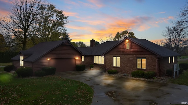 view of front facade featuring concrete driveway, brick siding, a chimney, and an attached garage