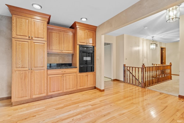 kitchen with dark countertops, hanging light fixtures, light wood-type flooring, a notable chandelier, and a warming drawer