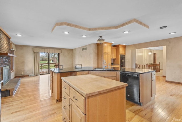 kitchen with light wood finished floors, dishwasher, a center island, a peninsula, and a sink