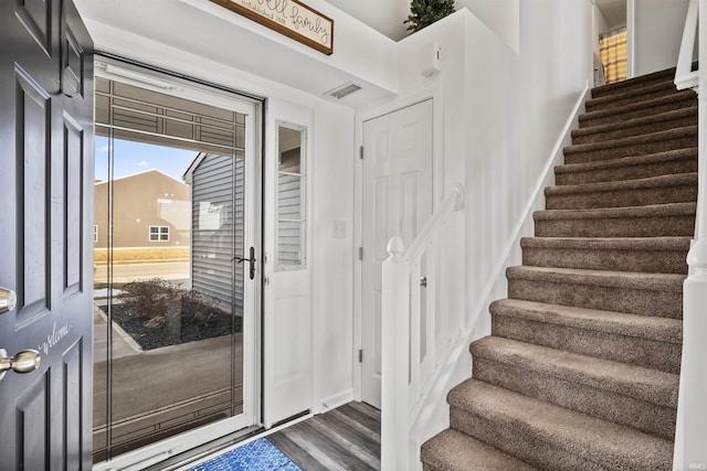 entryway with stairs, visible vents, and dark wood finished floors