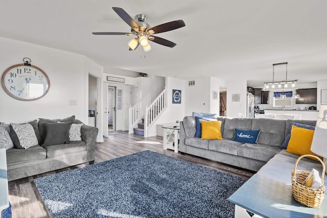 living room with ceiling fan, stairs, visible vents, and wood finished floors