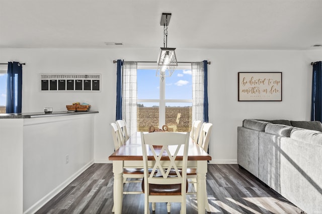 dining room with dark wood-type flooring, a chandelier, visible vents, and baseboards