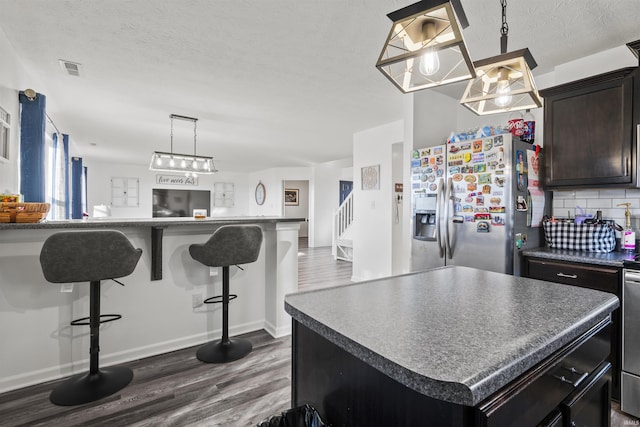 kitchen with a center island, tasteful backsplash, dark wood-type flooring, open floor plan, and stainless steel fridge