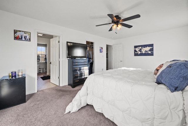 carpeted bedroom with ceiling fan, a spacious closet, and ensuite bathroom