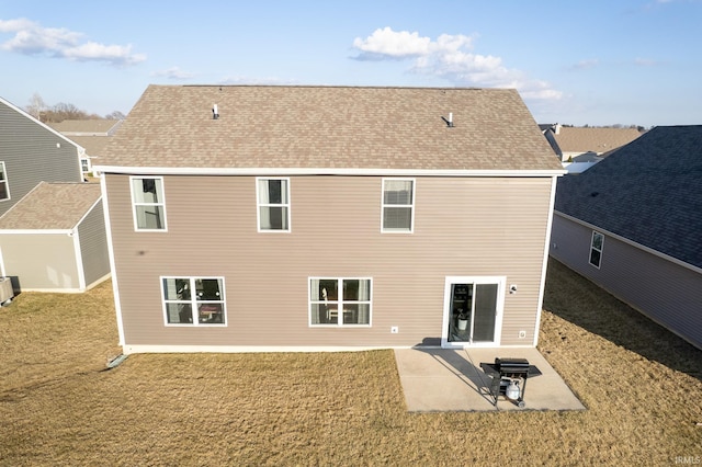 rear view of property featuring a yard, roof with shingles, and a patio area