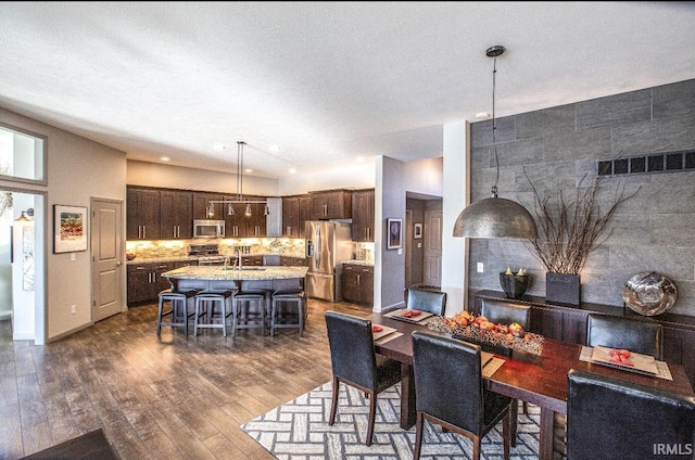 dining area with a textured ceiling, dark wood-type flooring, visible vents, and baseboards