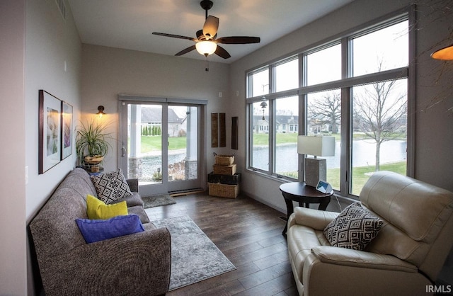 interior space featuring a water view, dark wood-style floors, a healthy amount of sunlight, and a ceiling fan