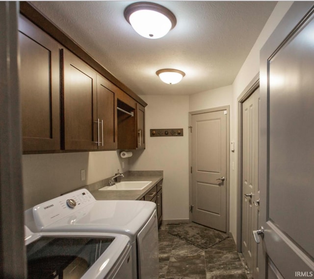 laundry room featuring cabinet space, a textured ceiling, a sink, and washing machine and clothes dryer