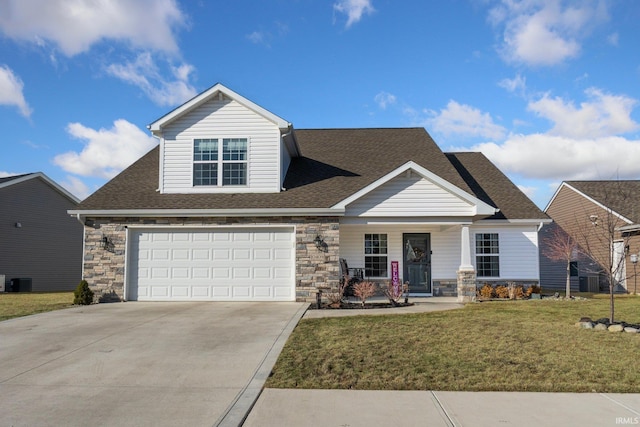 view of front facade with stone siding, a shingled roof, a front yard, and driveway